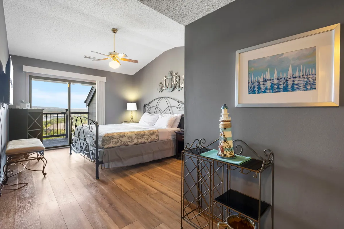 This image features a cozy bedroom with decorative bedding and a large window offering a scenic view. A decorative lighthouse figurine adds a touch of charm. Natural light fills the space, creating a calm and inviting atmosphere—ideal for relaxation and restful sleep.