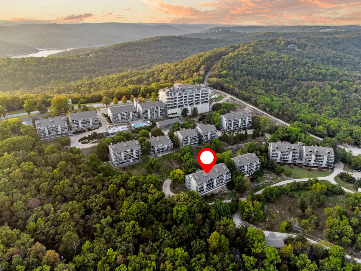 A wide exterior shot capturing lush greenery, scenic hills, and a developed residential area nestled into the landscape. The image hints at the abundance of outdoor recreation opportunities nearby, such as golf, hiking, and wildlife observation.