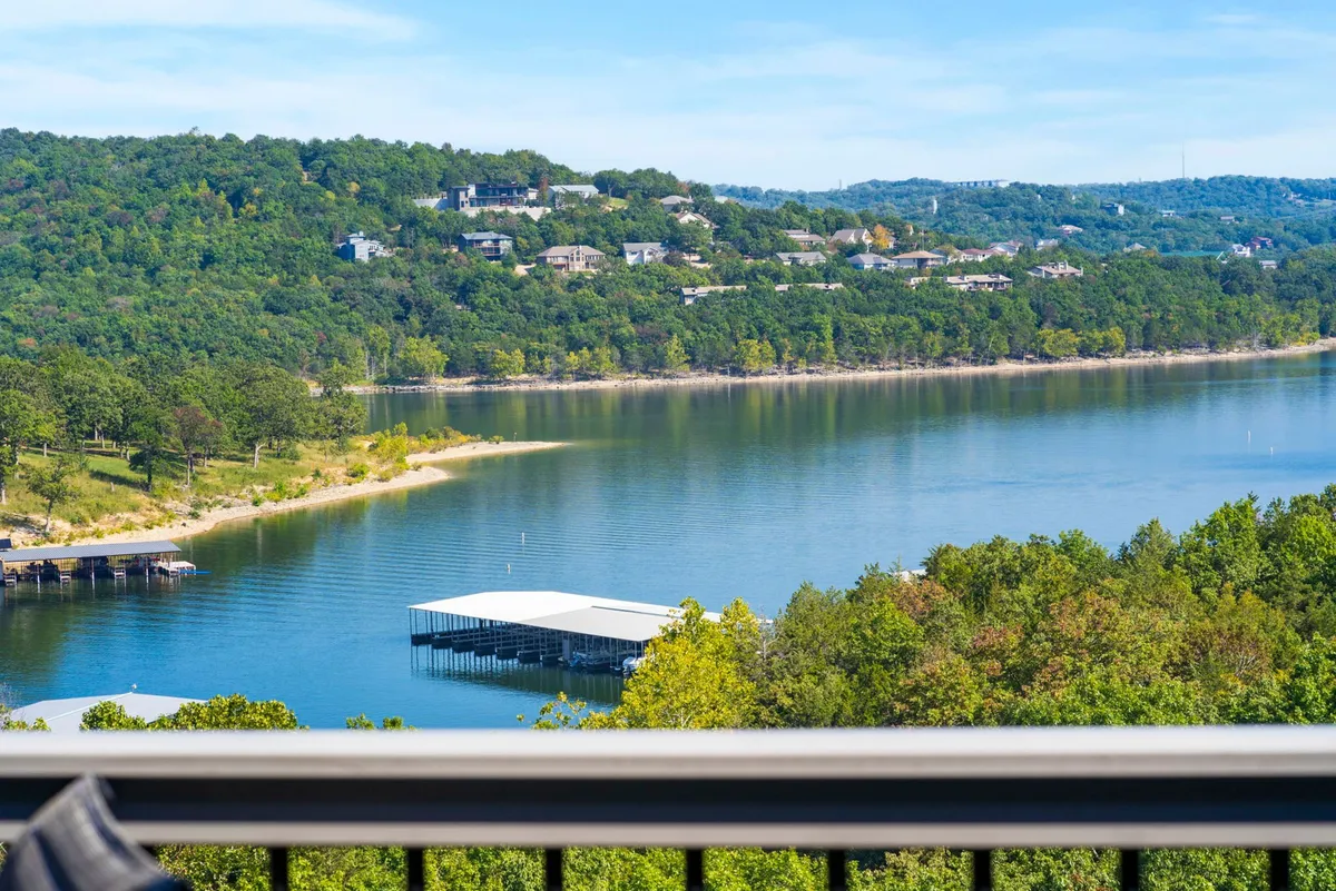 A broad view overlooking the lake, with the marina visible along the tree-lined shore and gentle hills in the background. The scene highlights the accessibility of the water, the presence of boats, and abundant greenery. The tranquil mood sets the tone for outdoor adventure and water activities.