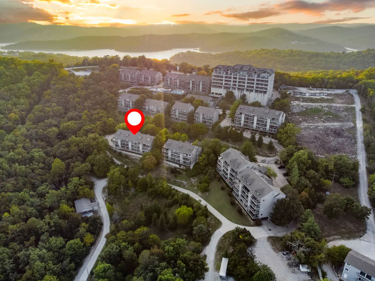 A wide exterior shot highlighting the cluster of condo buildings nestled among lush greenery and winding paths, evoking the feel of a peaceful, nature-connected community.