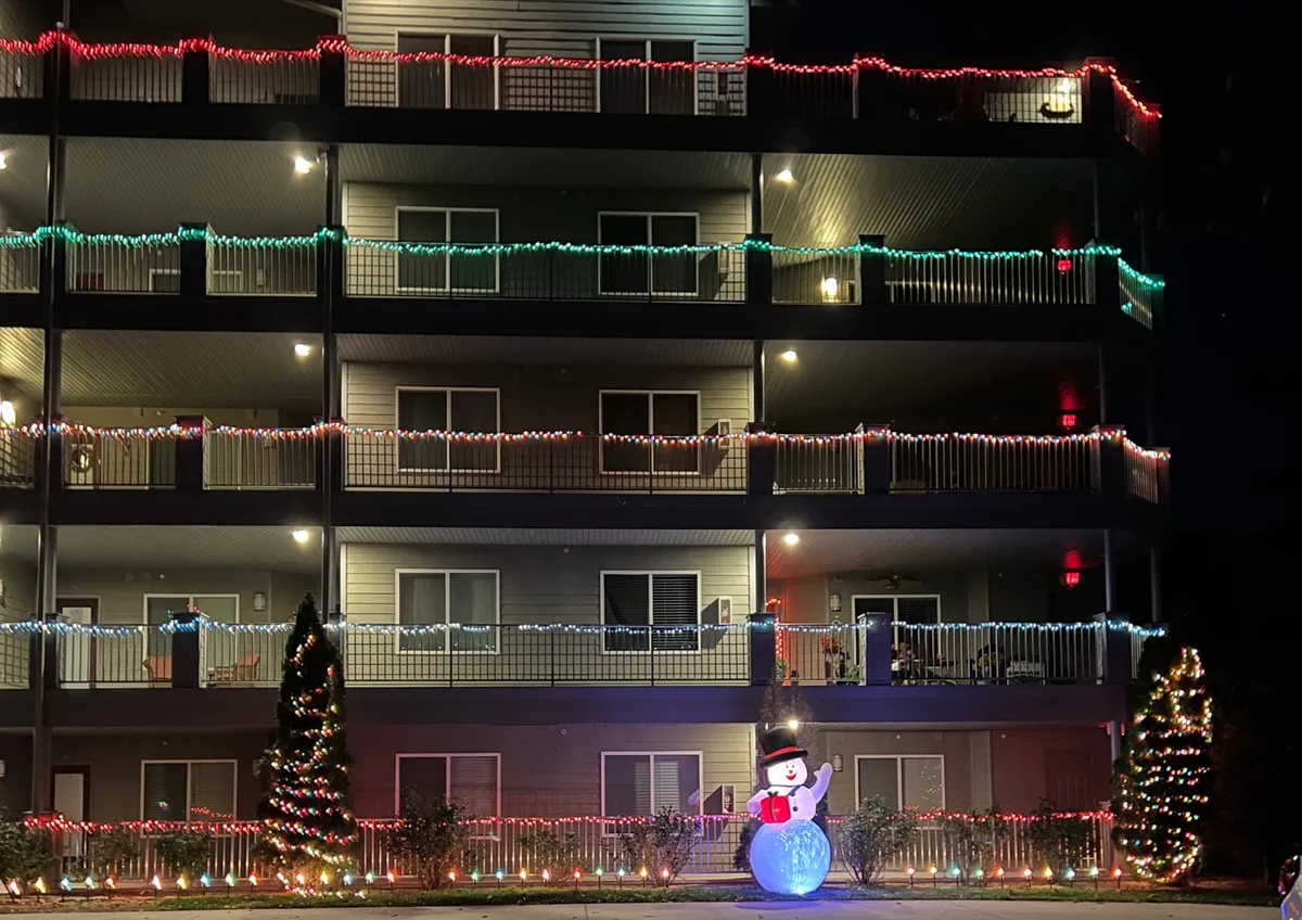 This image presents illuminated balconies, decorative Christmas lights, a snowman decoration, and a Christmas tree, emphasizing a joyful, holiday-ready exterior. The building's outdoor areas are vibrant with seasonal decor, perfect for family photo opportunities and evening strolls.
