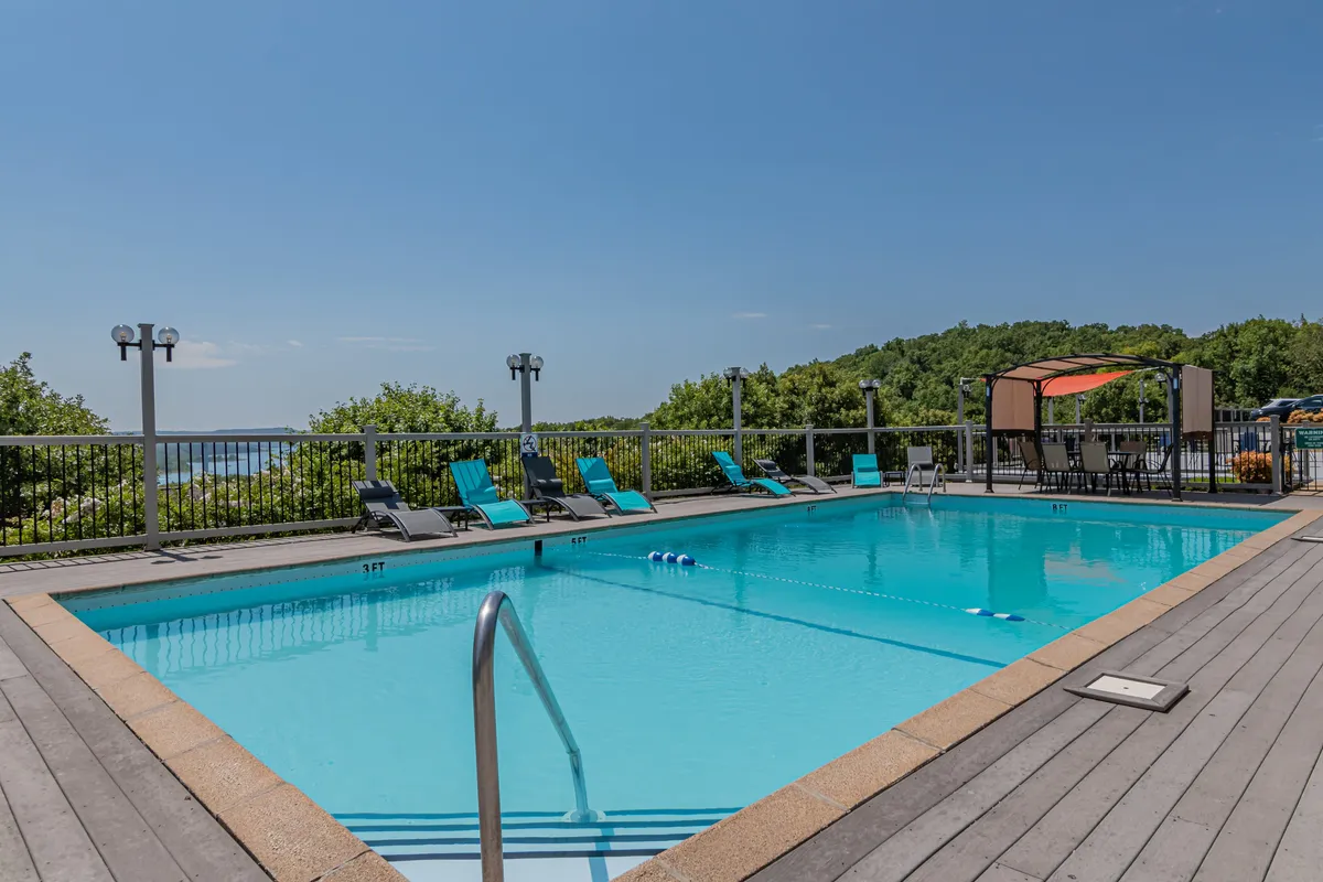 This exterior image features a sparkling outdoor swimming pool surrounded by lounge chairs, a canopy seating area, and lush greenery. The scene captures leisurely outdoor relaxation and the vibrant resort atmosphere.