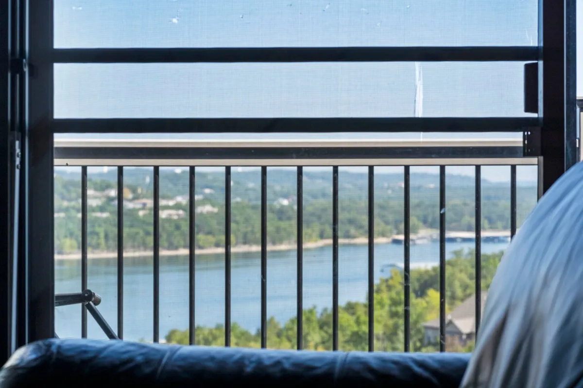 A tranquil balcony scene overlooking a distant water view and vibrant green landscape, with a simple railing in the foreground. The photo evokes the peacefulness of unwinding after a day of activities while offering scenic lake vistas.